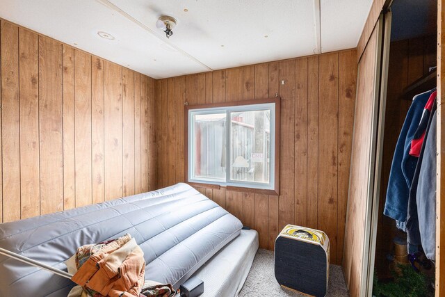 bedroom featuring carpet flooring and wood walls