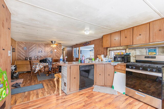 kitchen with dishwasher, light wood-type flooring, gas stove, and wood walls