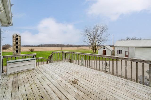 wooden deck with a rural view and an outbuilding