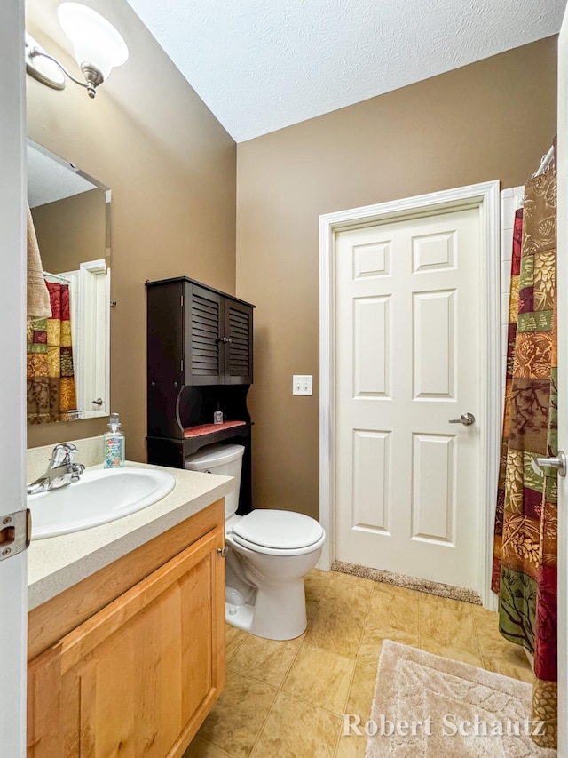 bathroom with vanity, toilet, and a textured ceiling