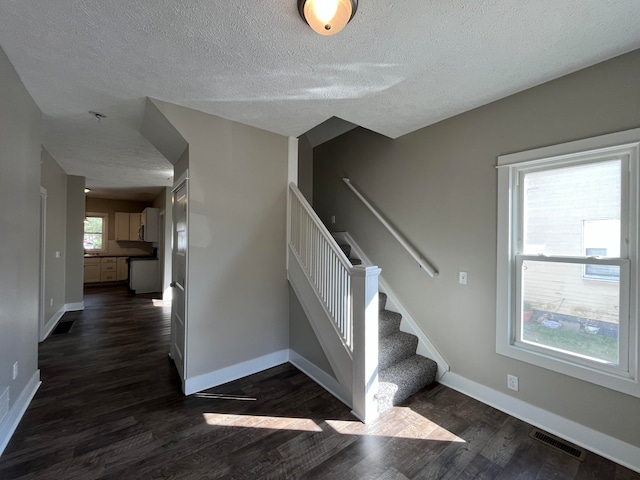 stairway with hardwood / wood-style floors and a textured ceiling