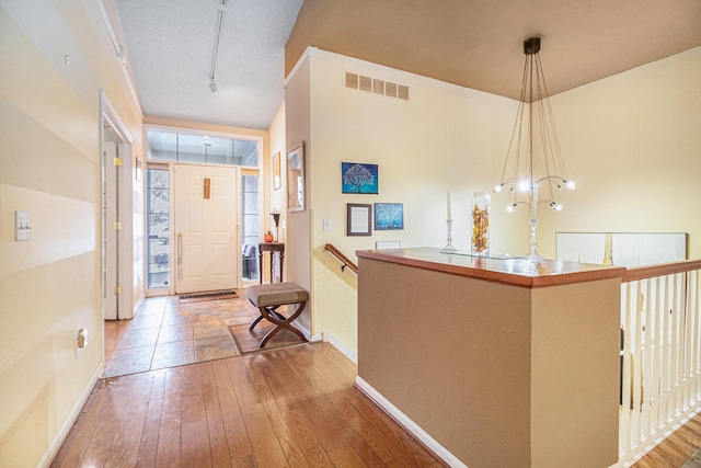 entrance foyer featuring a notable chandelier, a textured ceiling, and light wood-type flooring