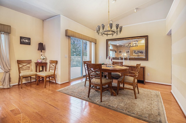 dining room with light hardwood / wood-style floors, lofted ceiling, and a notable chandelier