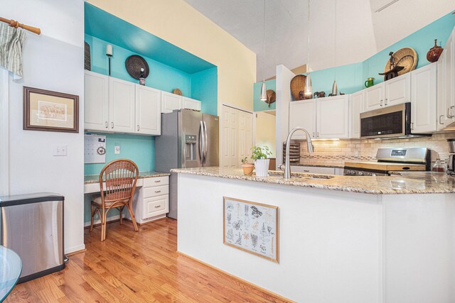 kitchen with sink, light stone countertops, light wood-type flooring, white cabinetry, and stainless steel appliances