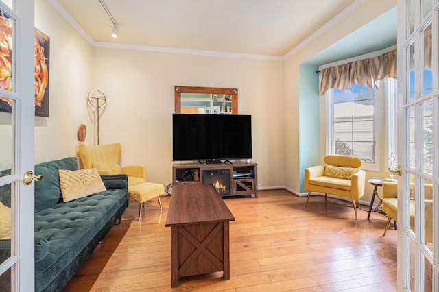 living room featuring hardwood / wood-style floors, crown molding, rail lighting, and french doors