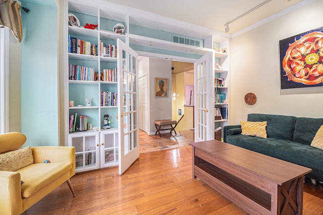 living room featuring french doors, ornamental molding, and light hardwood / wood-style flooring