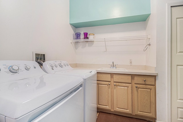 clothes washing area featuring washing machine and dryer, sink, and cabinets