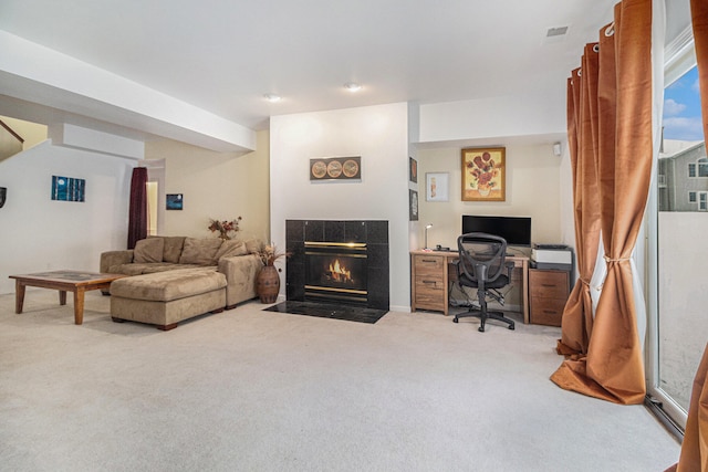 home office with light colored carpet and a tiled fireplace