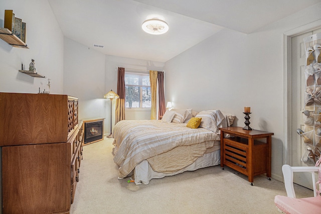 bedroom with light colored carpet and lofted ceiling