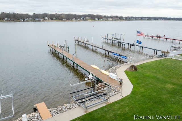 view of dock featuring a water view, boat lift, and a lawn