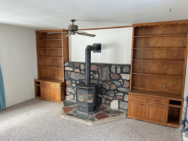 details with carpet flooring, ceiling fan, a wood stove, and crown molding