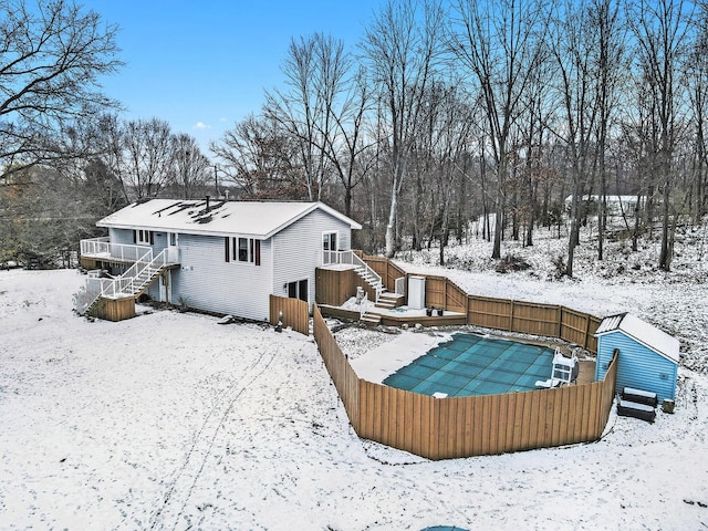 snow covered rear of property with a wooden deck