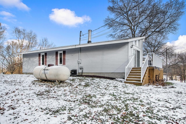 snow covered house featuring central AC