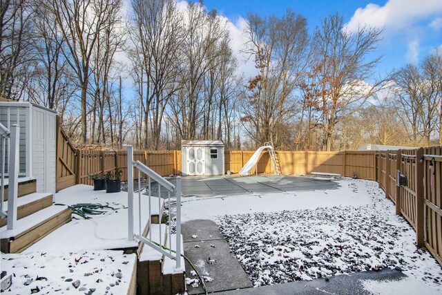 yard covered in snow featuring a shed and a covered pool