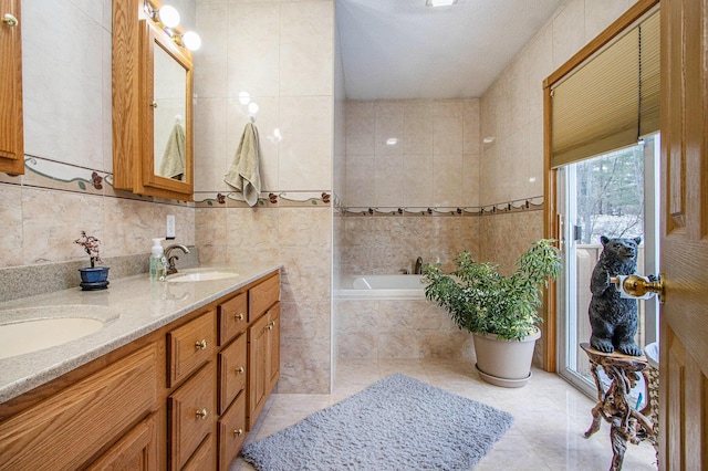 bathroom with tiled tub, tile patterned flooring, vanity, and tile walls