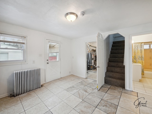 tiled foyer entrance featuring radiator heating unit and water heater