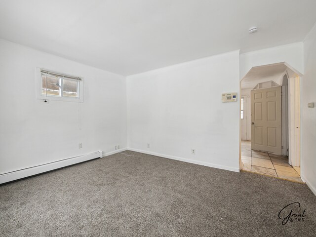 unfurnished room featuring light colored carpet and a baseboard heating unit