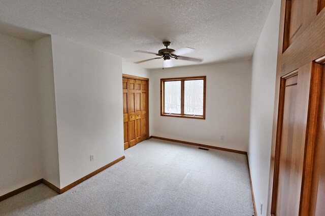 unfurnished bedroom with ceiling fan, a closet, light carpet, and a textured ceiling