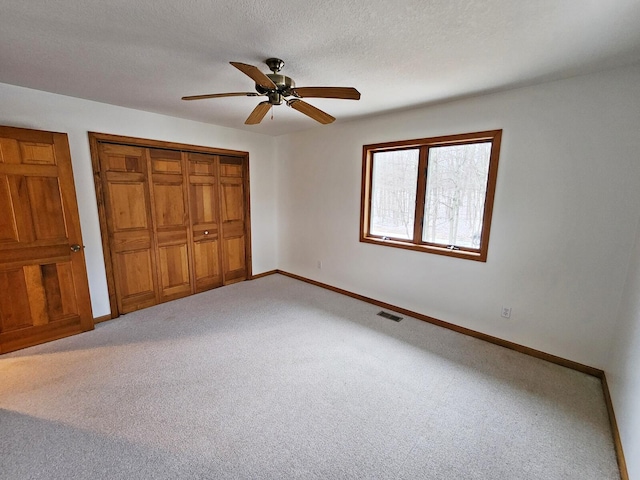 unfurnished bedroom with ceiling fan, a closet, carpet, and a textured ceiling