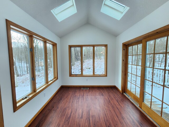 interior space with a wealth of natural light, vaulted ceiling with skylight, and dark wood-type flooring