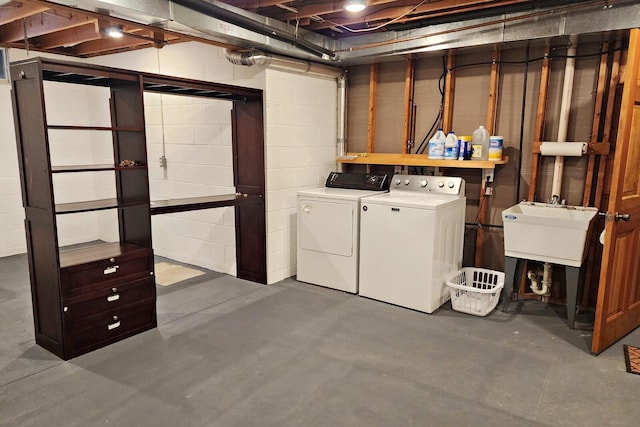 unfinished below grade area with concrete block wall, washer and clothes dryer, and a sink