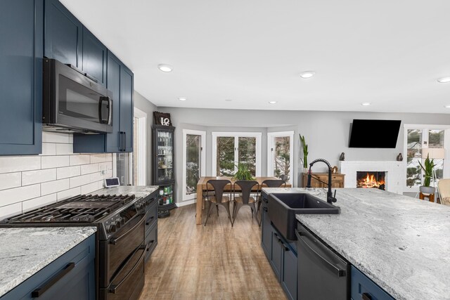 kitchen featuring appliances with stainless steel finishes, blue cabinets, a wealth of natural light, and sink