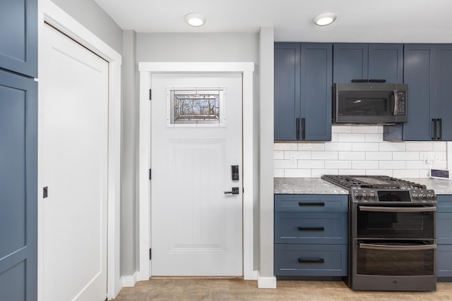 kitchen with light stone countertops, appliances with stainless steel finishes, decorative backsplash, and blue cabinetry