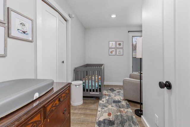 bedroom with a closet, dark wood-type flooring, and a nursery area