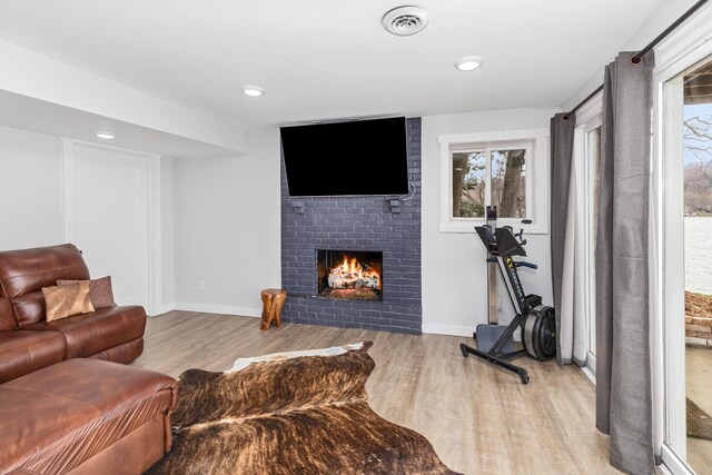 living room with light hardwood / wood-style floors and a brick fireplace