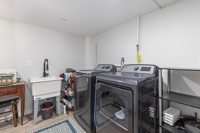 laundry area with light hardwood / wood-style flooring and washing machine and clothes dryer