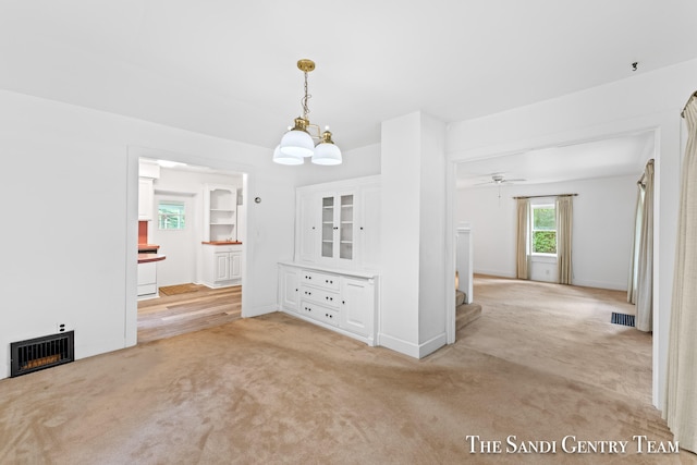 interior space featuring light carpet and ceiling fan with notable chandelier