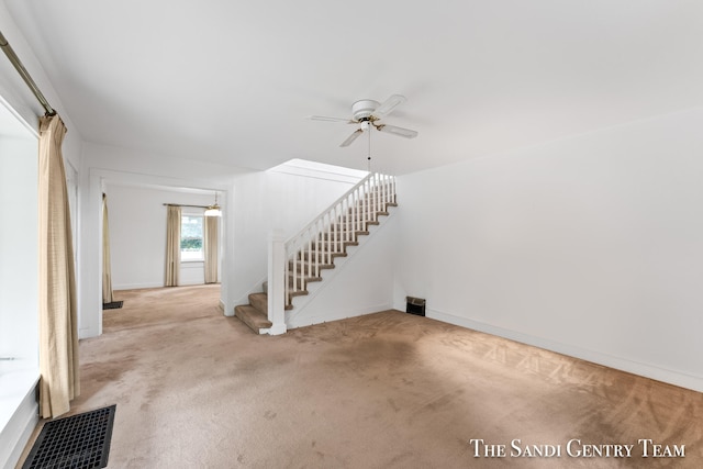 unfurnished living room with light colored carpet and ceiling fan