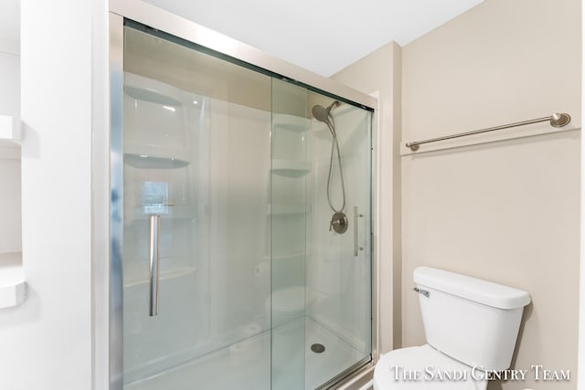 bathroom with toilet and a shower with shower door