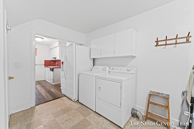 laundry area featuring cabinets, sink, light wood-type flooring, and independent washer and dryer