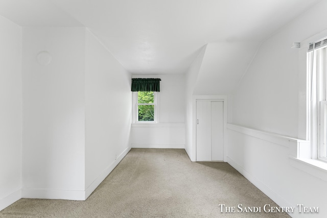 carpeted empty room with lofted ceiling