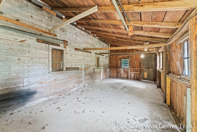 interior space with vaulted ceiling and wood walls