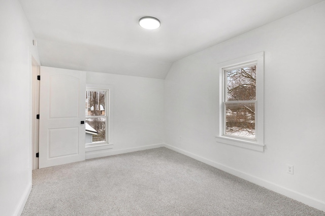 spare room with light colored carpet and lofted ceiling