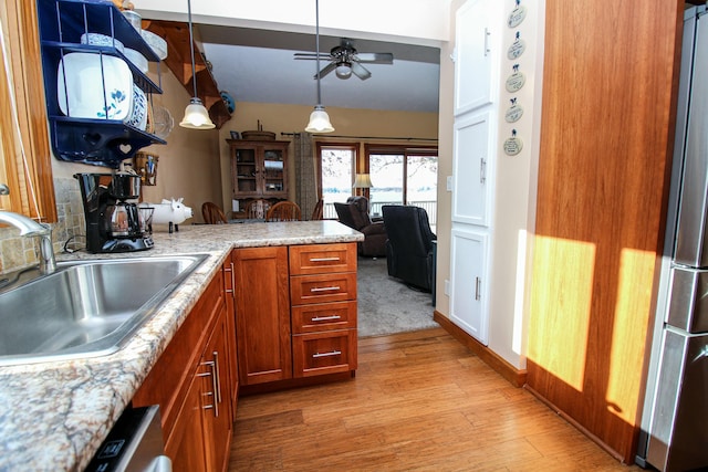 kitchen featuring sink, ceiling fan, light wood-type flooring, decorative light fixtures, and stainless steel refrigerator