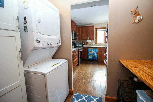 laundry area with hardwood / wood-style floors and stacked washer / drying machine