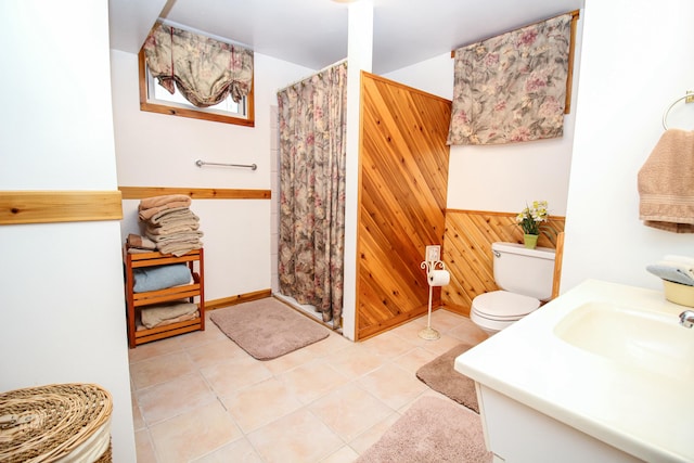 bathroom with curtained shower, tile patterned floors, wood walls, toilet, and vanity