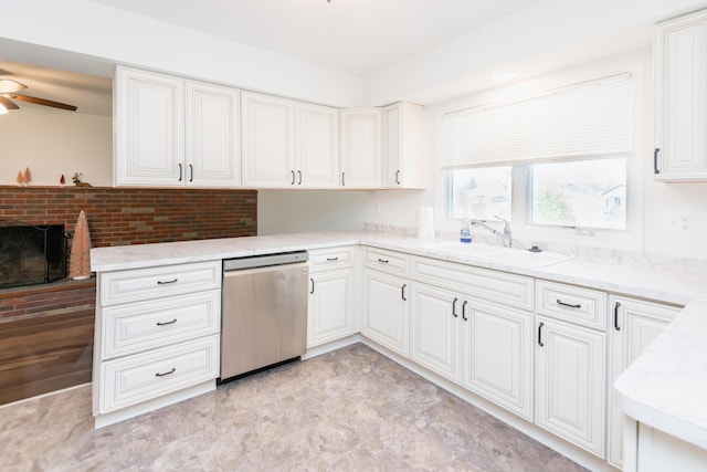 kitchen with ceiling fan, sink, a brick fireplace, stainless steel dishwasher, and white cabinets