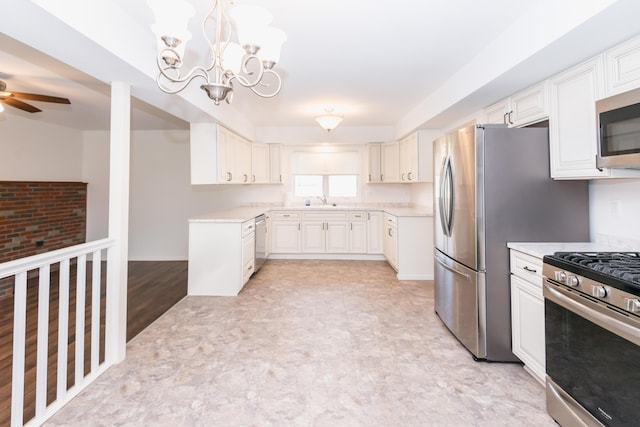 kitchen featuring ceiling fan with notable chandelier, hanging light fixtures, sink, appliances with stainless steel finishes, and white cabinetry