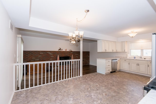 kitchen with a brick fireplace, stainless steel appliances, sink, pendant lighting, and a notable chandelier