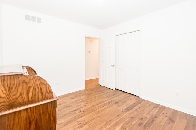 unfurnished bedroom with light wood-type flooring and a closet