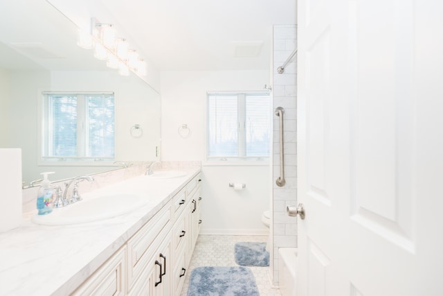 bathroom with tile patterned flooring, vanity, toilet, and a tile shower