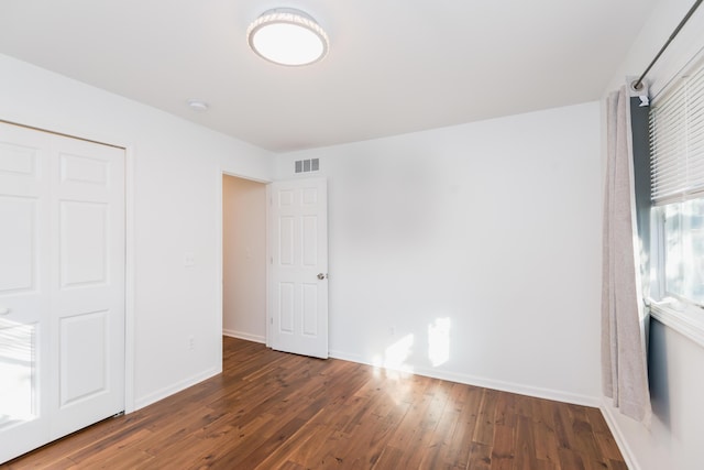 unfurnished bedroom featuring a closet and dark hardwood / wood-style floors