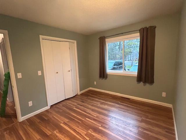 unfurnished bedroom featuring a textured ceiling, a closet, and dark hardwood / wood-style flooring