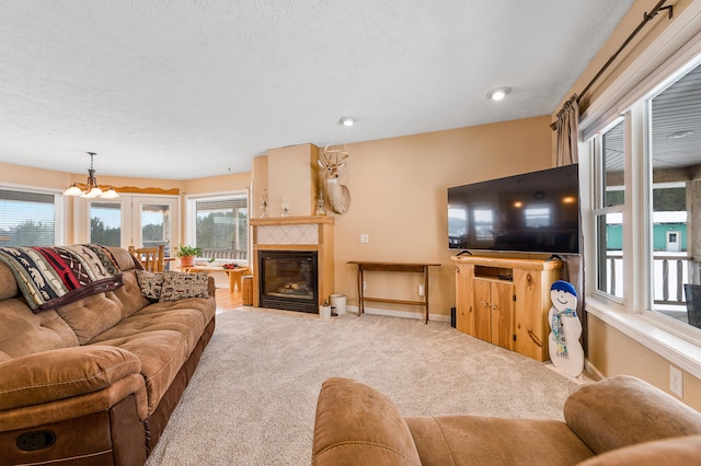 living room featuring a fireplace, a textured ceiling, carpet floors, and an inviting chandelier