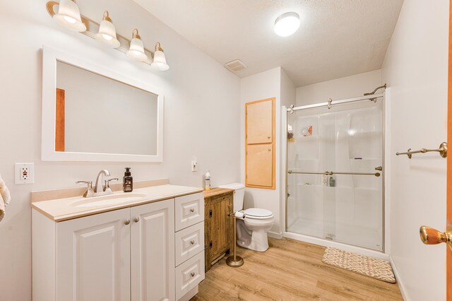 bathroom featuring walk in shower, a textured ceiling, toilet, vanity, and hardwood / wood-style flooring