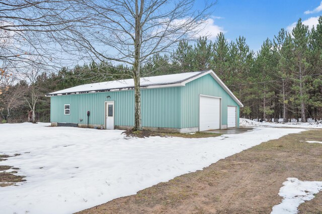 snow covered structure featuring a garage